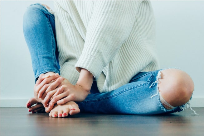 The bottom half of a woman sitting down with her legs crossed.